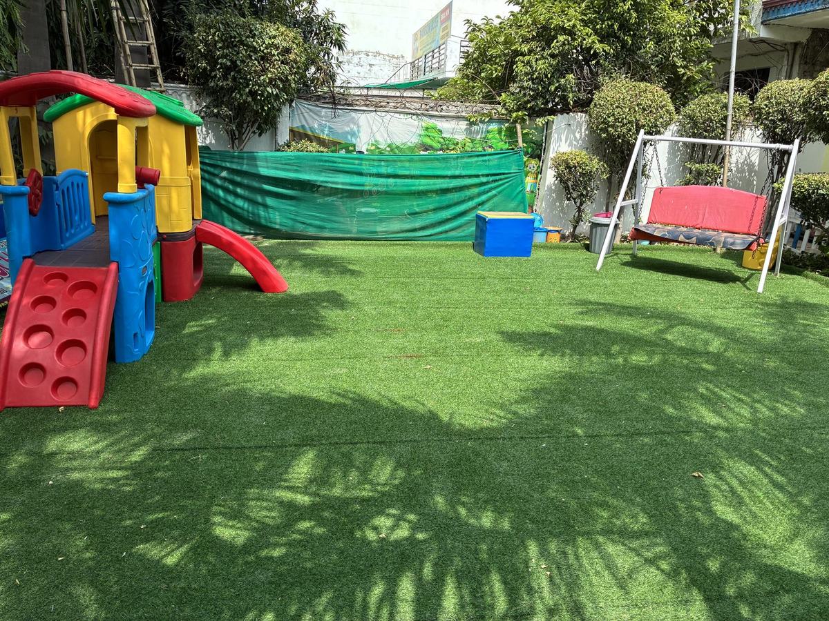 Outdoor play area with a playhouse slide, swing and artificial turf lawn